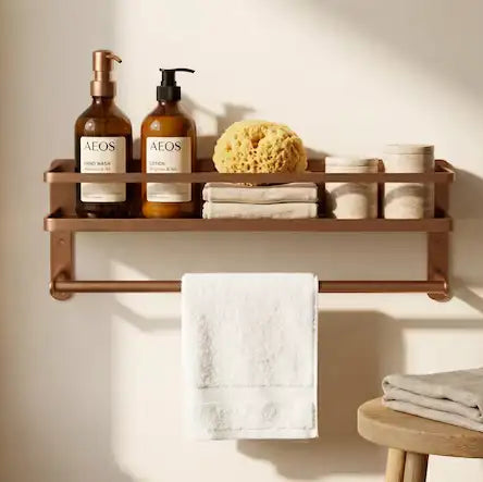 Bathroom shelf with Neom products, towels, and a stool against a light wall.